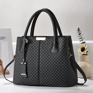 Detailed close-up of a black patterned tote bag with gold metal hardware and leather straps