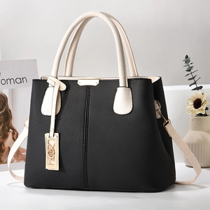 Close-up of black and cream contrast handbag with pebbled leather texture and gold hardware