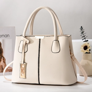 Close-up of cream faux leather handbag with lychee texture and gold-tone metal hardware