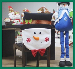 Detailed view of snowman chair cover with red sequin bow and winter holly hat