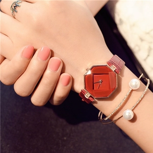 Close-up of women's octagonal red faceted watch with gold case and matching accessories