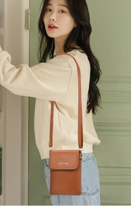 Detailed close-up of a caramel brown leather mini crossbody bag with logo on flap