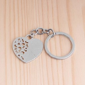Macro shot of silver heart-shaped keychain with tree of life cutout on wood background