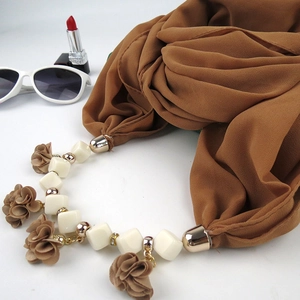 Brown floral pendant scarf necklace with gold beads and white squares on white background