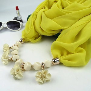 Detailed shot of yellow chiffon scarf necklace with beige beads and fabric floral pendant
