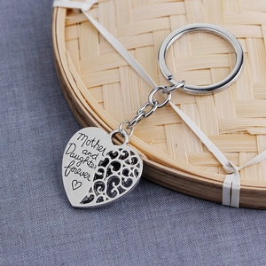 Silver heart keychain engraved with Mother and Daughter Forever on woven tray