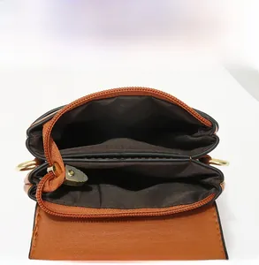 Detailed view of caramel leather crossbody bag with dual compartments and gold metal hardware