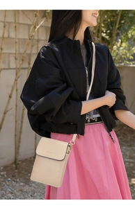 Detail of elegant beige crossbody bag showing logo lettering and gold hardware