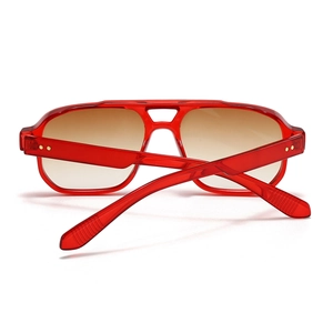 Macro detail of red translucent square pilot sunglasses with double bridge and gold rivets