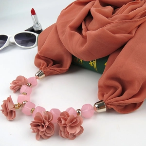 Detail of terracotta silk scarf necklace with pink flowers next to fashion accessories