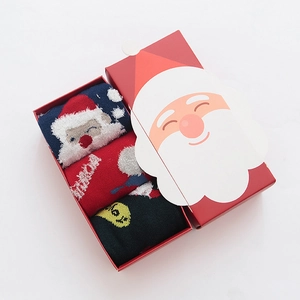Three pairs of Christmas socks with Santa and reindeer motifs in a red gift box