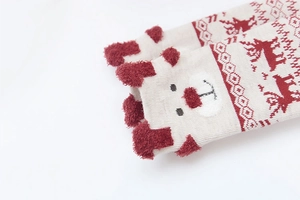 Close-up of children's Christmas socks with pom-poms, beige and red bear deer patterns
