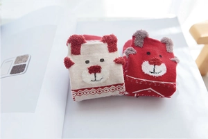 Detail shot of soft knit baby Christmas socks with cute bear faces on a book
