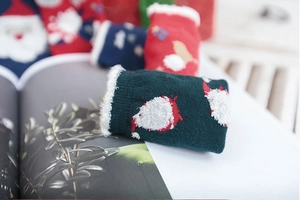 Close-up of green knit Christmas socks with Santa Claus pattern and white fuzzy trim