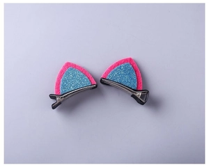 Close-up of pink felt cat ear hair clips with blue glitter inlay on black metal clips
