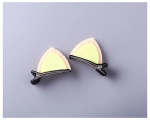 Detail view of peach and lime green felt cat ear hair clips on black metal crocodile clips
