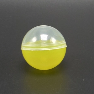 Detail of 45mm round plastic toy capsule with clear top and vibrant yellow base