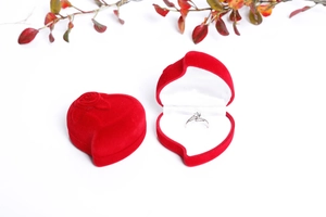 Close-up of red heart velvet jewelry box with 3D rose and silver ring inside