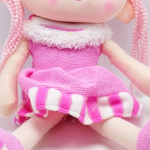 Detailed view of pink knitted braids and plush textured dress on a cute rag doll toy