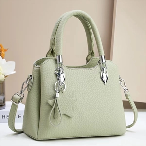 Detail of mint green bucket bag featuring pebbled leather texture and star charm accessory