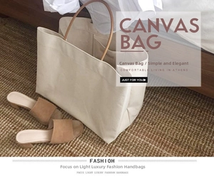 Detail shot of large beige canvas tote bag with brown straps on a woven rug