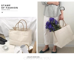 Detail of a minimalist large off-white canvas tote bag with brown slim handles and lifestyle setting