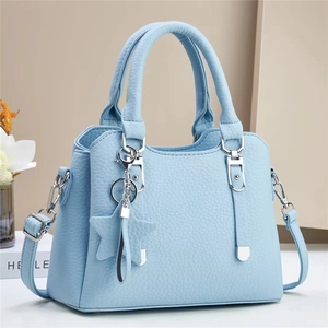 Minimalist light blue handbag with star pendant and silver hardware in soft lighting