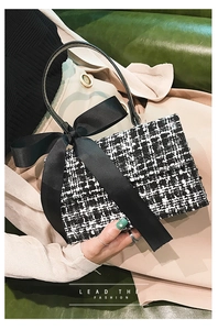 Close-up of black and white tweed handbag with a large bow detail and sleek top handle