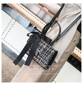 Detail of tweed crossbody bag featuring a large black bow and silver metallic twist lock