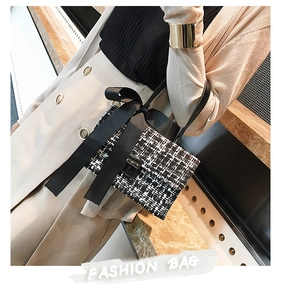 Detail of a chic tweed handbag featuring a large satin bow and golden metal clasp