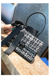 Detail of tweed crossbody bag with a large black bow and elegant metal square clasp