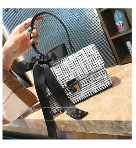 Macro detail of plaid tweed handbag featuring a large black satin bow and metal clasp