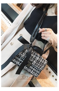 Detailed view of black and white tweed square bag with a large ribbon bow and metal lock