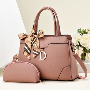 Détail du sac à main en cuir rose poudré avec pendentif doré et foulard en soie