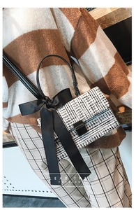 Close-up of checkered tweed handbag with silk bow handle and metallic twist lock