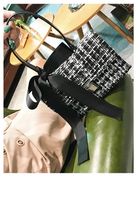 Macro view of black and white tweed fabric texture with a large satin bow on a mini bag