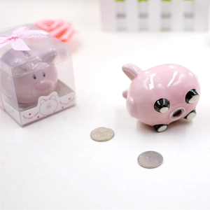 Detail showing a pink ceramic piggy bank in a clear gift box with a pink ribbon