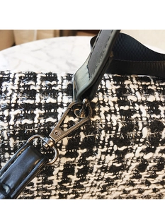 Macro shot of gunmetal lobster clasp on black and white tweed crossbody bag strap