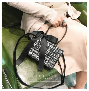 Close-up of black and white tweed crossbody bag with a large satin bow decoration