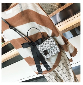 Detail of tweed crossbody bag with black silk bow and metal buckle on model