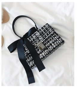 Detailed view of black and white tweed handbag featuring a large satin bow and metal lock