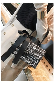 Detail of tweed handbag with black bow decoration and metallic turn-lock closure