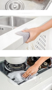 Close-up of grey wave pattern disposable dishcloth cleaning a greasy kitchen stovetop