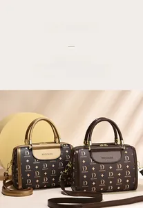 Detail of Boston handbag featuring brown monogram faux leather and golden metal hardware
