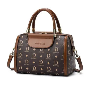 Classic dark brown Boston bag with monogram pattern shown in a stylish outdoor cafe setting