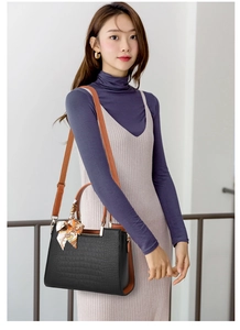 Chic handbag in black crocodile pattern with brown handles and a silk scarf accent