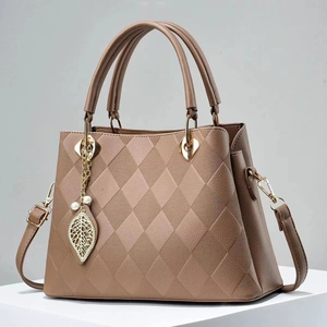 Detailed close-up of khaki quilted handbag with golden leaf charm and textured surface