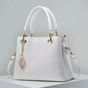 Close-up of white lychee leather texture with quilted stitching and golden leaf charm