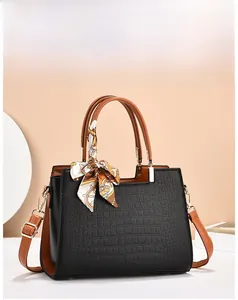 Close-up of black crocodile pattern handbag with brown handles and floral silk scarf
