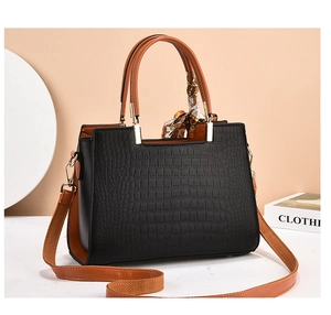 Detail of black crocodile pattern leather handbag with floral silk scarf and gold hardware